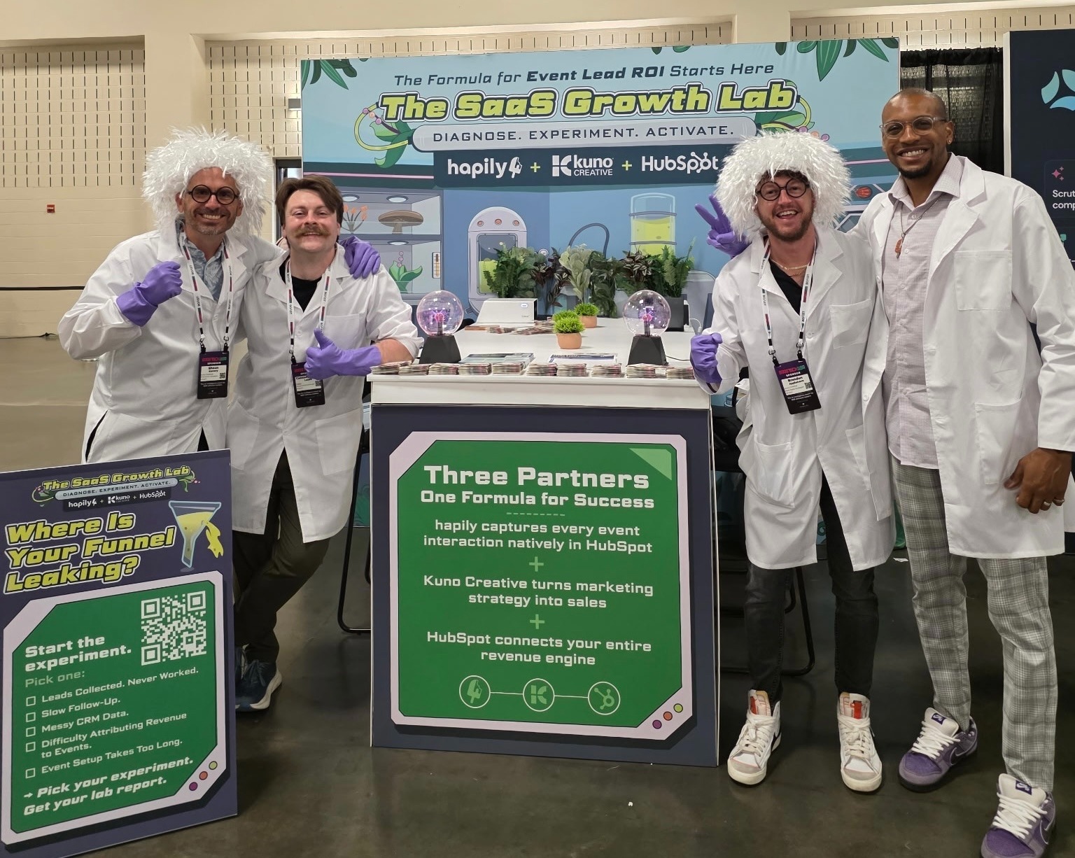 A picture of team members dressed as mad scientists at the SaaStock 2026 booth.